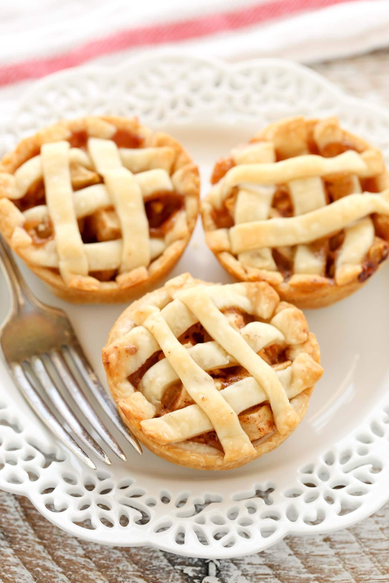 A close up view of three mini apple pies on a white plate.