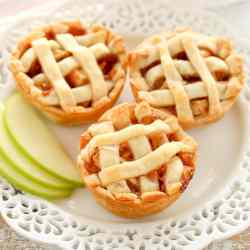Three mini apple pies on a decorative white plate.