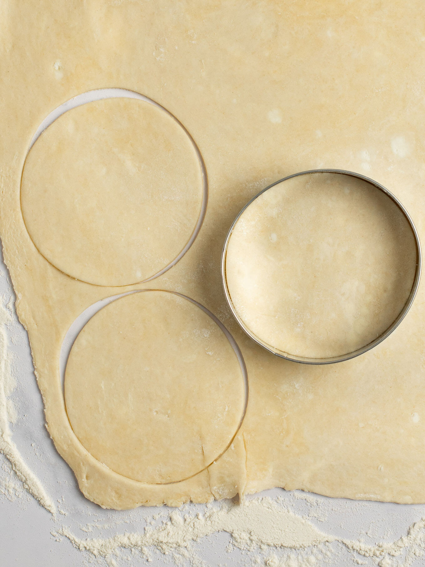 An overhead view of pie crust being cut into 3.5-inch circles.