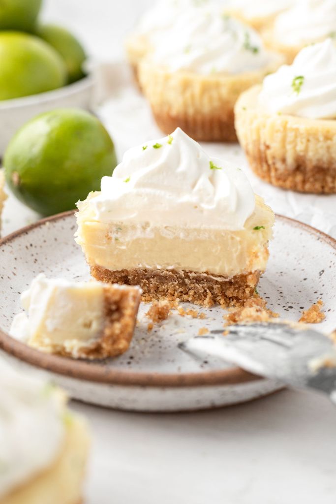 A mini key lime pie on a speckled dessert plate, cut in half to show the layers. 