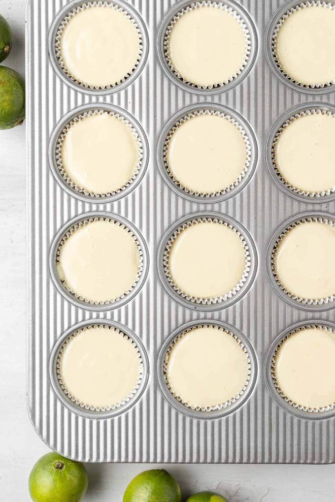 An overhead view of unbaked mini key lime pies in a muffin tin.