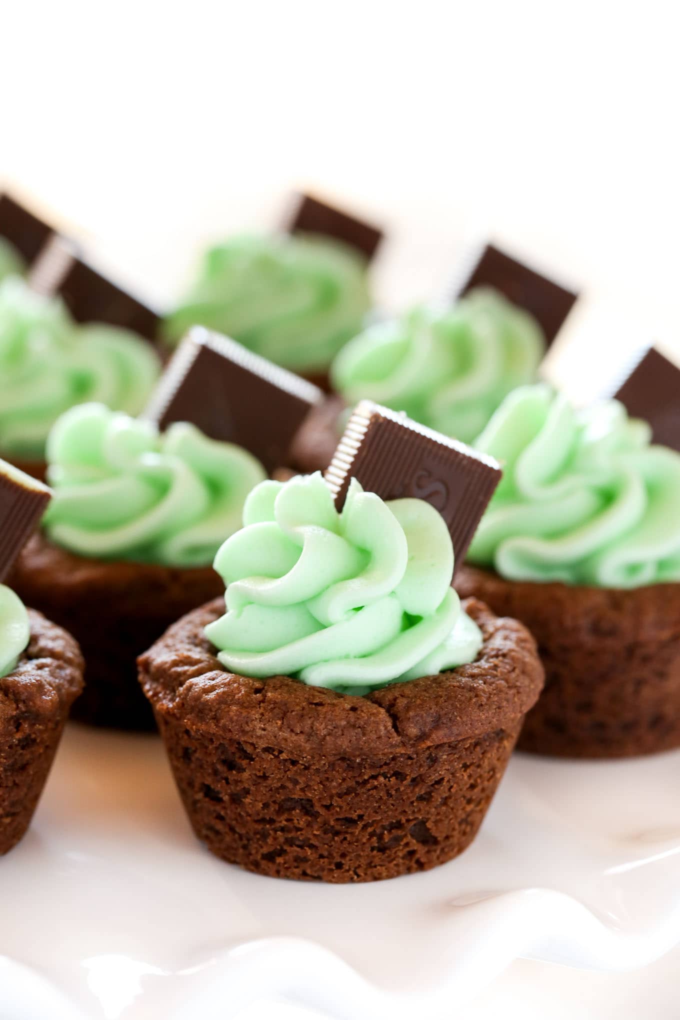 Chocolate cookie cups filled with an easy mint frosting and topped with an andes mint. These Mint Chocolate Cookie Cups are a perfect treat for St. Patrick's Day or mint chocolate lovers!