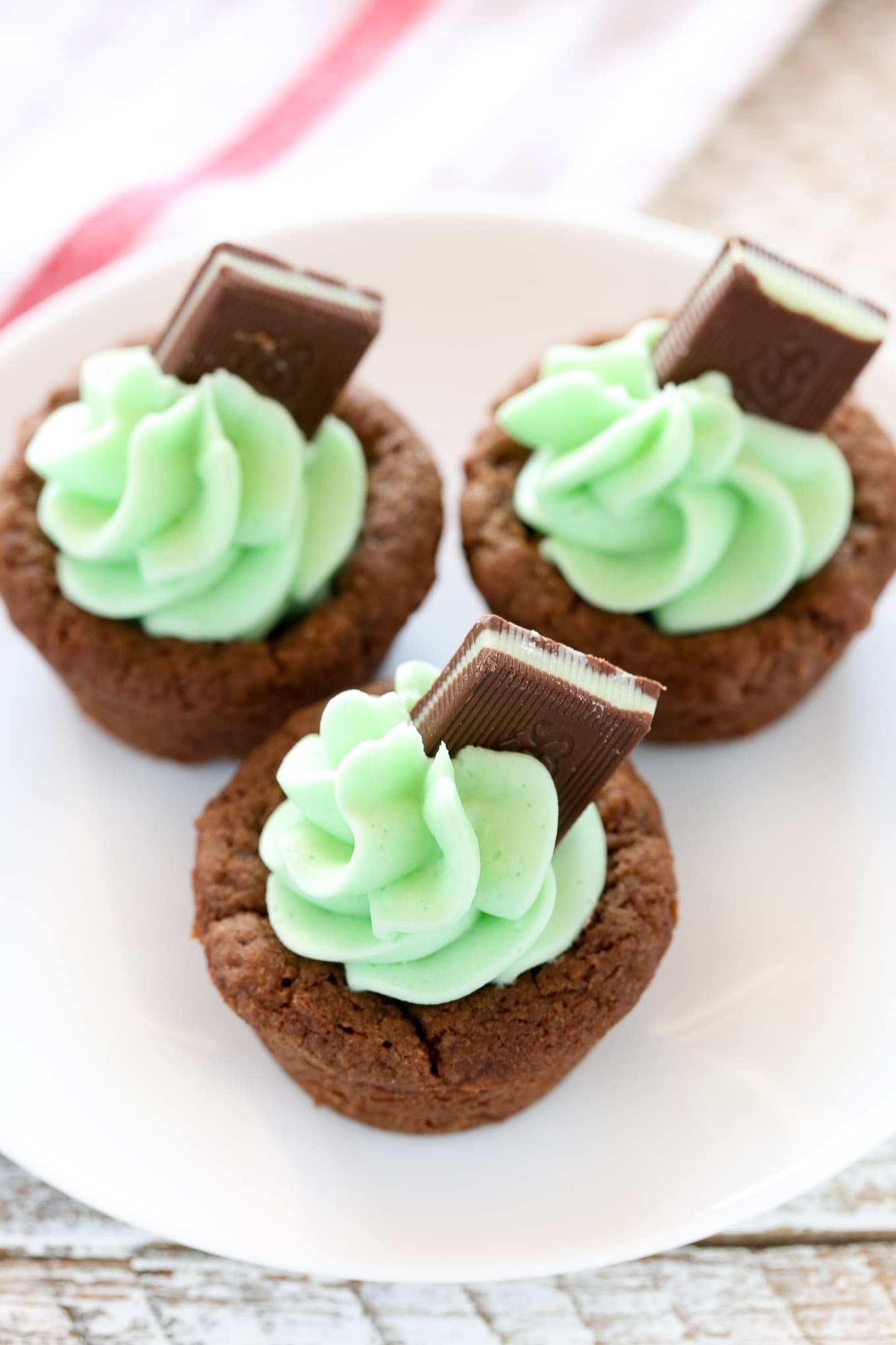 Chocolate cookie cups filled with an easy mint frosting and topped with an andes mint. These Mint Chocolate Cookie Cups are a perfect treat for St. Patrick's Day or mint chocolate lovers!