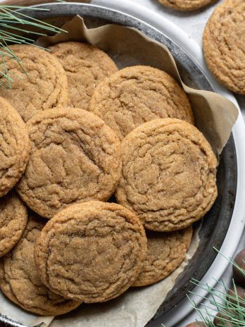 A baking pan lined with parchment paper and filled with soft molasses cookies.