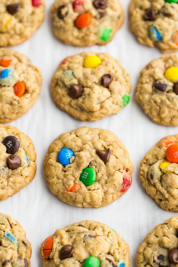 Baked monster cookies lined up on a piece of parchment paper.