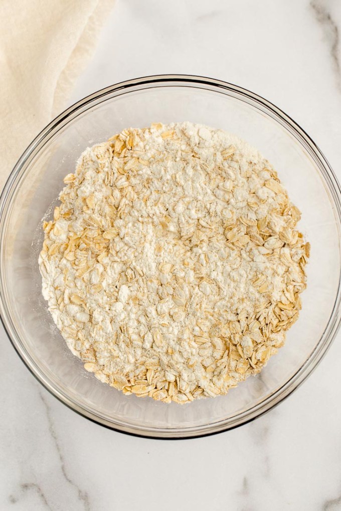 A glass bowl with the dry ingredients mixed together for monster cookies.