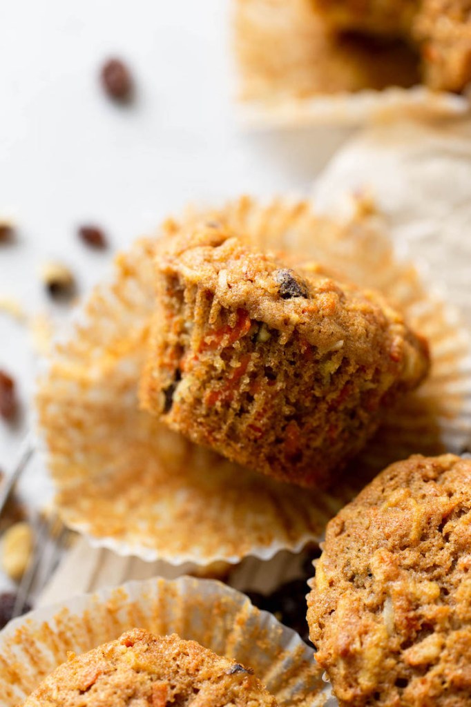 Close up shot of a morning glory muffin that's been turned on its side in the muffin liner. More muffins peep out in the foreground. 