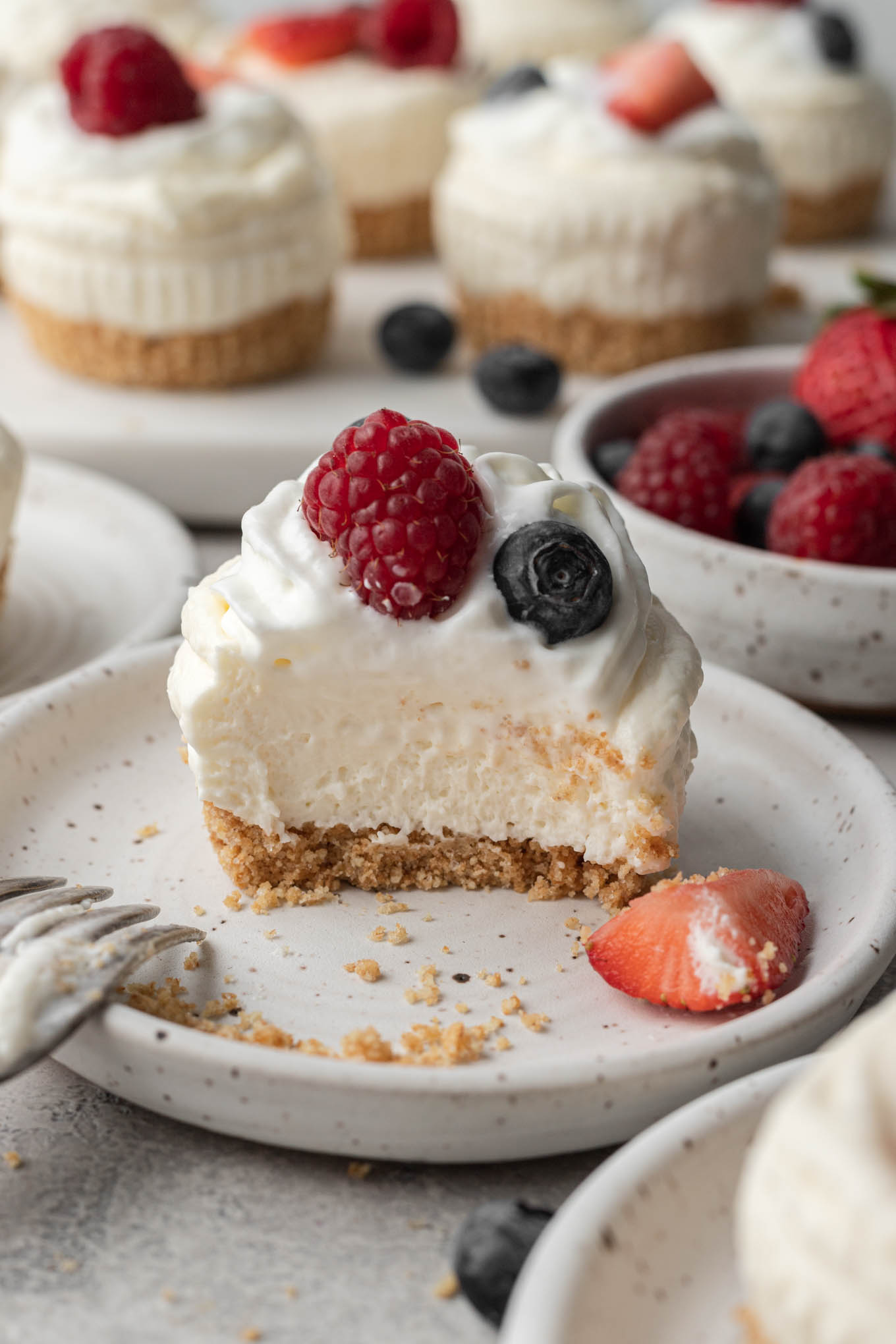 The side profile of a no bake mini cheesecake, with a bite missing. 