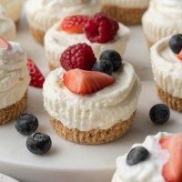 Several no-bake mini cheesecakes topped with fresh berries.