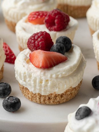 Several no-bake mini cheesecakes topped with fresh berries.