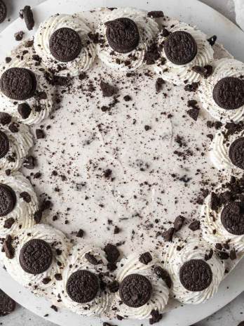 An overhead view of a no-bake Oreo cheesecake topped with whipped cream and mini Oreos.