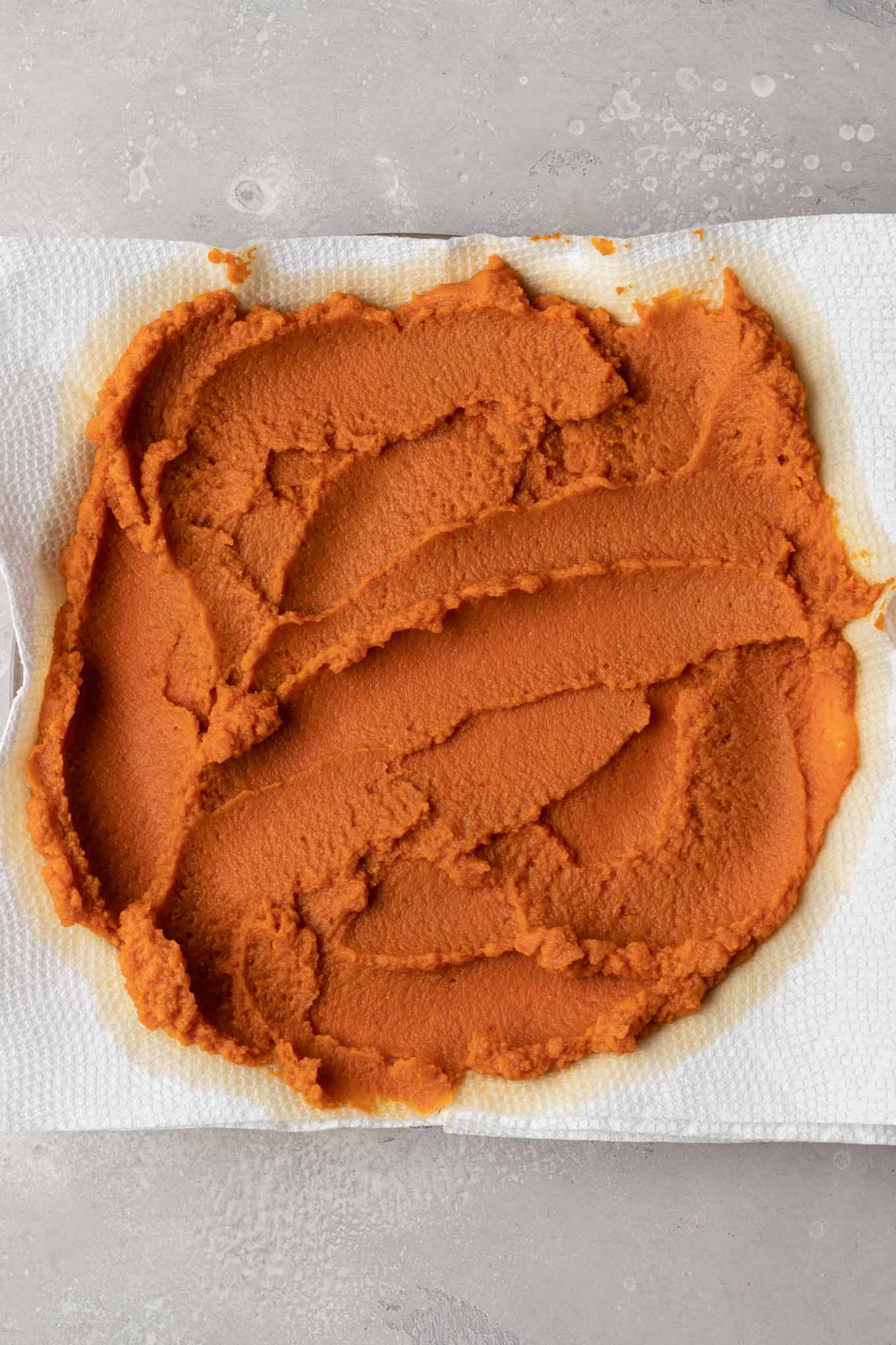 An overhead view of pumpkin puree spread over paper towels. 
