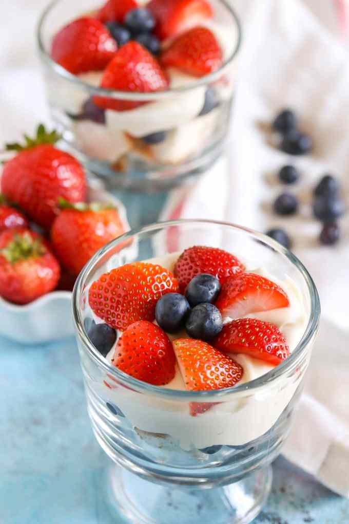 A small glass dish filled with angel food cake trifle. Another mini trifle and a dish of strawberries rests in the background. 