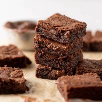 A stack of Nutella brownies on a piece of parchment paper. More brownies surround the stack.