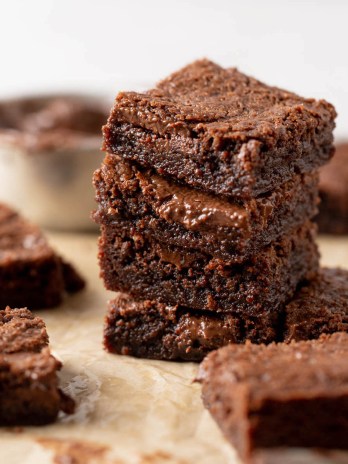 A stack of Nutella brownies on a piece of parchment paper. More brownies surround the stack.