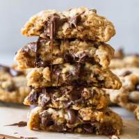 A stack of oatmeal chocolate chip cookies cut in half with melted chocolate running down the front.