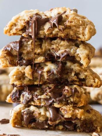 A stack of oatmeal chocolate chip cookies cut in half with melted chocolate running down the front.