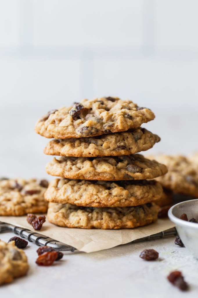 A stack of oatmeal raisin cookies on a cooling rack lined with parchment paper.
