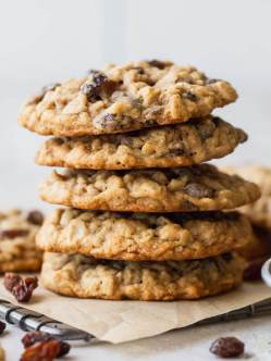 A stack of oatmeal raisin cookies on top of a small cooling rack lined with parchment paper.