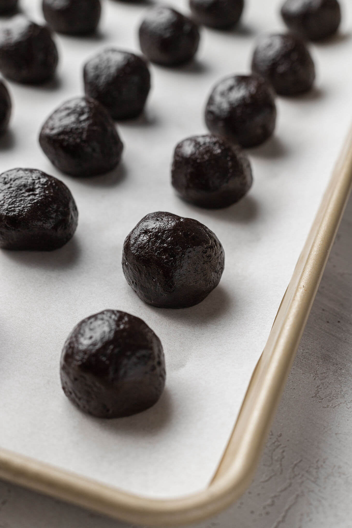 Rolled Oreo cream cheese balls on a parchment-lined baking sheet.