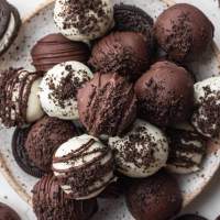 A plate with several Oreo balls covered in white chocolate and semi-sweet chocolate.