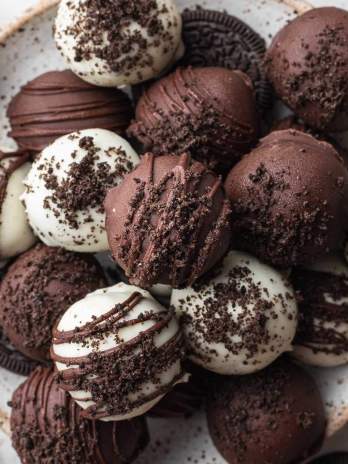 A plate with several Oreo balls covered in white chocolate and semi-sweet chocolate.