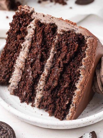 A slice of Oreo cake on a white speckled plate.