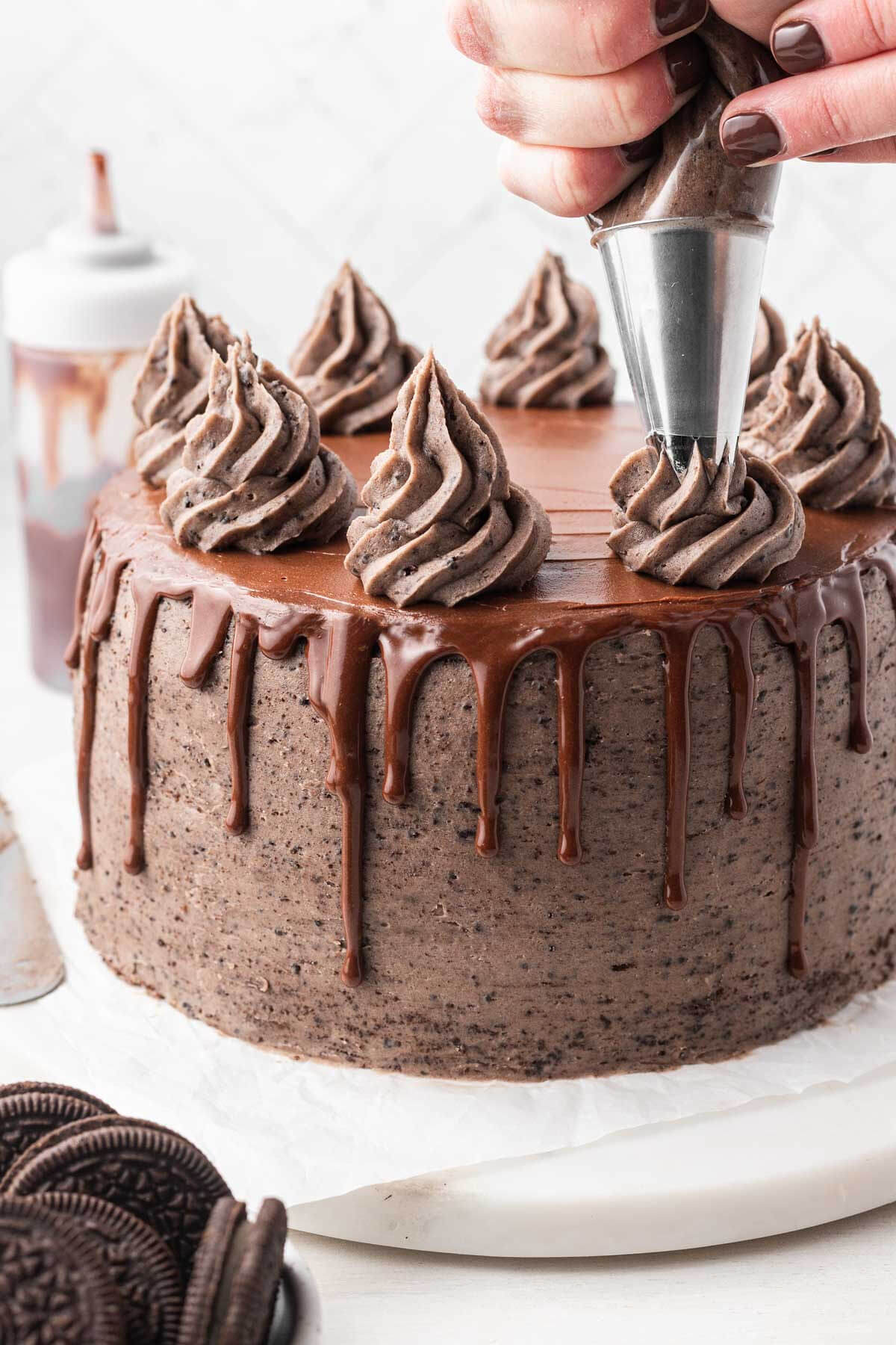 Swirls of Oreo frosting being piped on top of a layer cake.