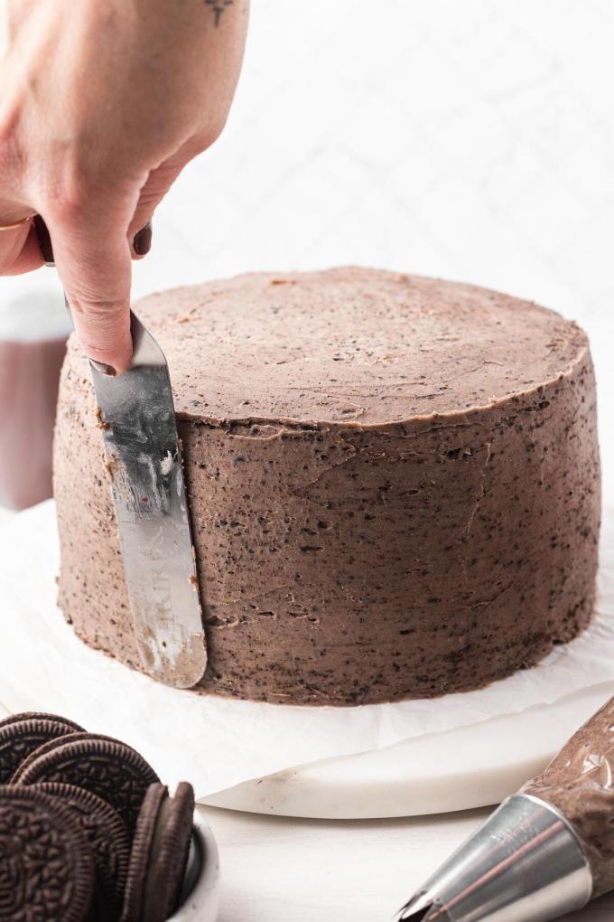 Oreo frosting being smoothed out on a layer cake.