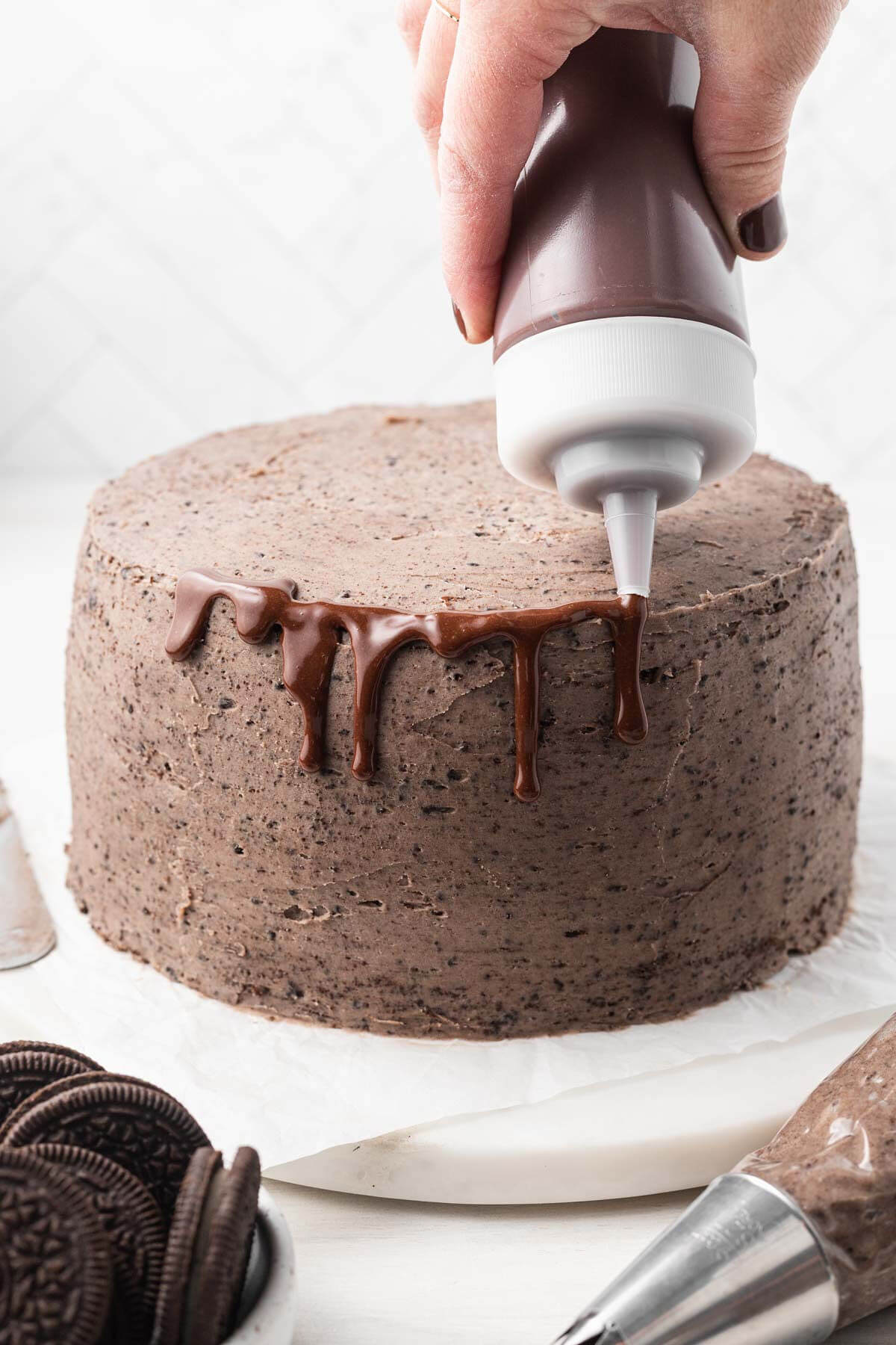 A process shot showing chocolate ganache being dripped down the sides of a cake.