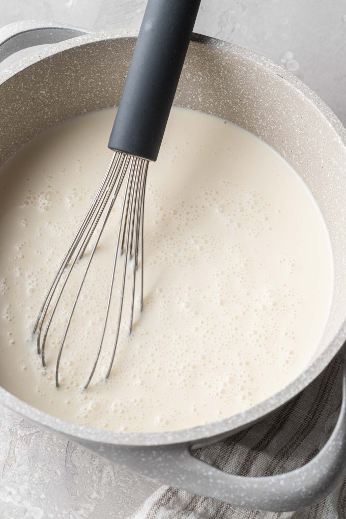 A saucepan of panna cotta mixture, with a wire whisk.