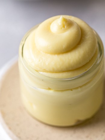 A small glass jar filled with vanilla pastry cream. The jar rests on an overturned bowl.