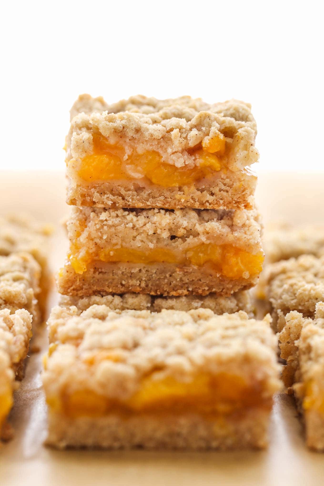 A stack of peach crumble bars, with additional bars surrounding the stack. 