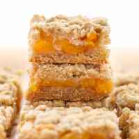 A stack of peach crumble bars, with additional bars surrounding the stack.