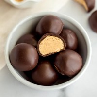A small white bowl filled with peanut butter balls.
