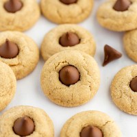 Several peanut butter blossoms on top of a piece of parchment paper.