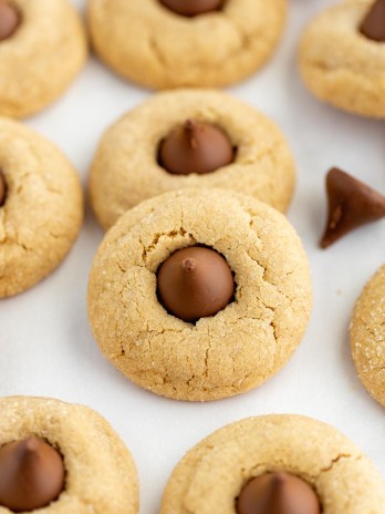 Several peanut butter blossoms on top of a piece of parchment paper.