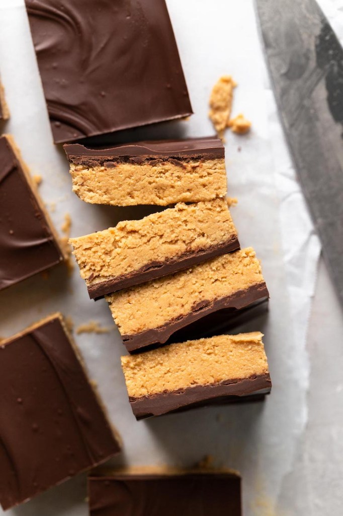 Four slices of chocolate peanut butter bars, lying on their sides. Unsliced bars surround them. 