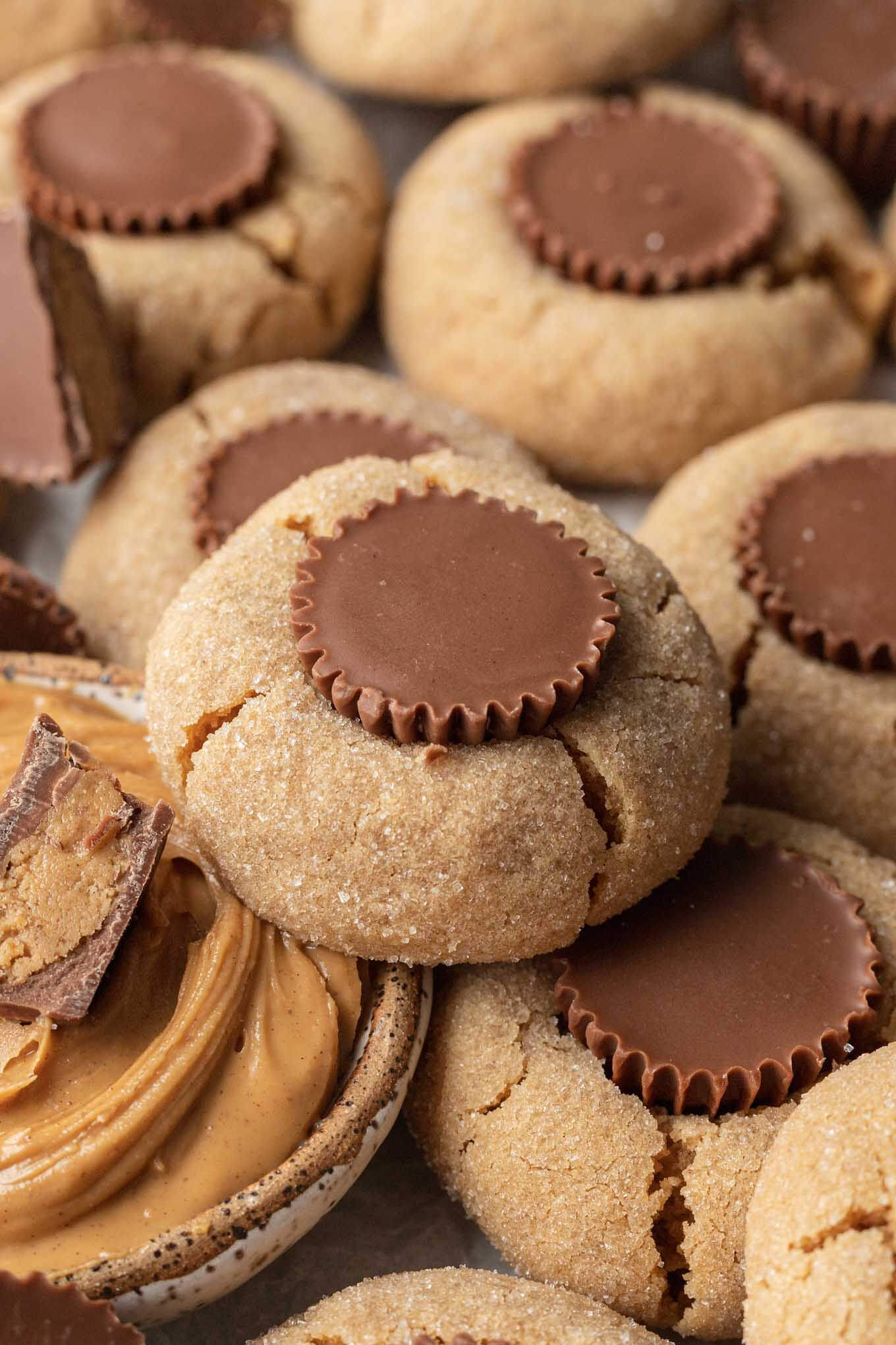 An array of peanut butter cookies with peanut butter cups, with a dish of peanut butter in the center. 