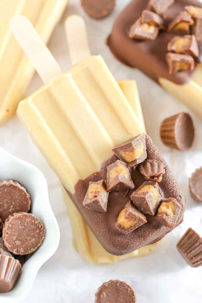 Peanut butter popsicles topped with magic shell and mini peanut butter cups. These Peanut Butter Cup Pudding Pops are a delicious and easy summer treat!