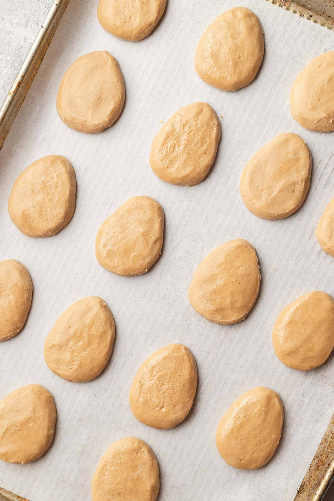 An overhead view of shaped peanut butter eggs on a baking tray.