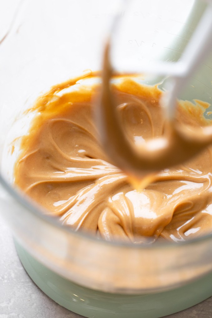 A glass mixing bowl holding butter and peanut butter mixed together.