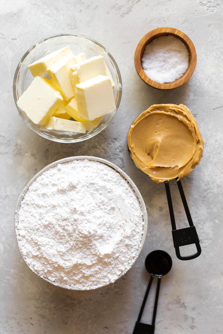 The ingredients needed to make peanut butter fudge laid out on a rustic gray surface.