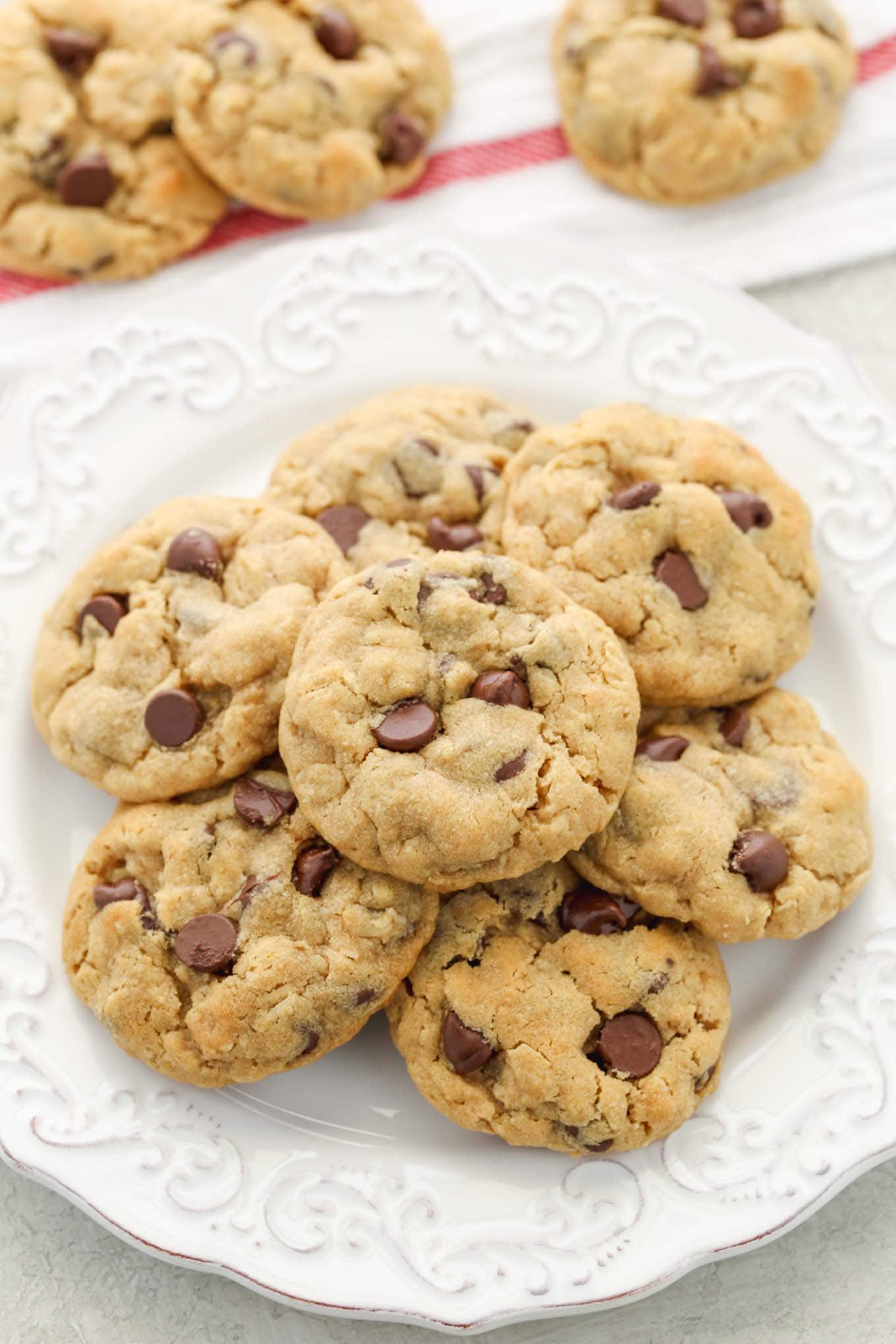 A stack of peanut butter oatmeal chocolate chip cookies on a plate with more cookies in the background.