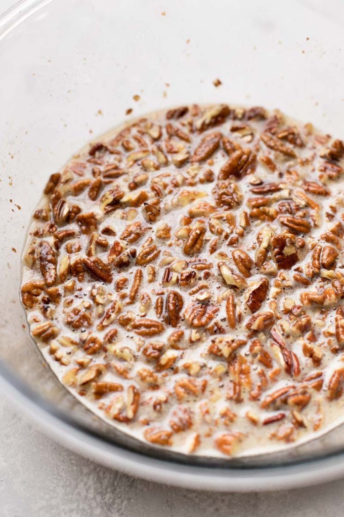 A glass mixing bowl holding pecan pie filling.
