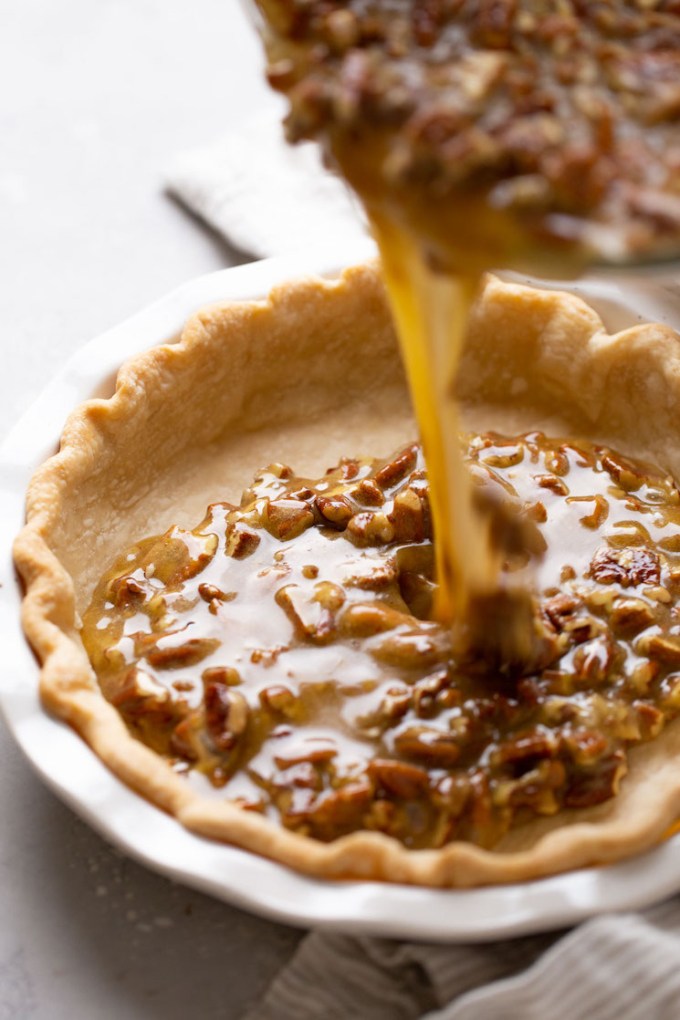 Pecan pie filling being poured into a pie crust.