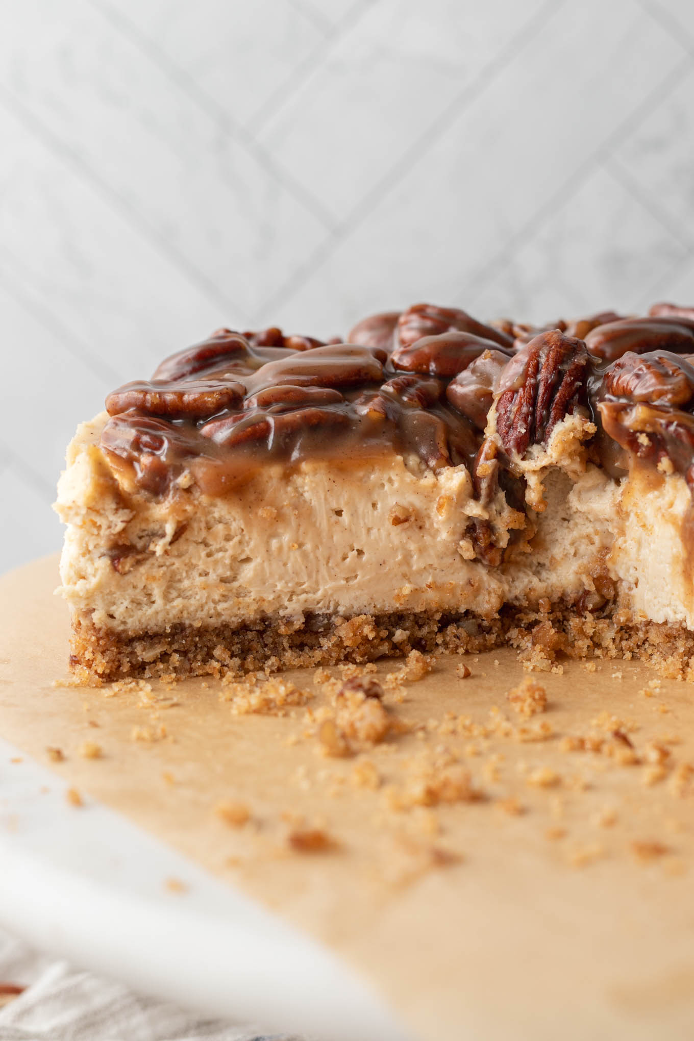 A pecan pie cheesecake, sliced and shown from the side. 