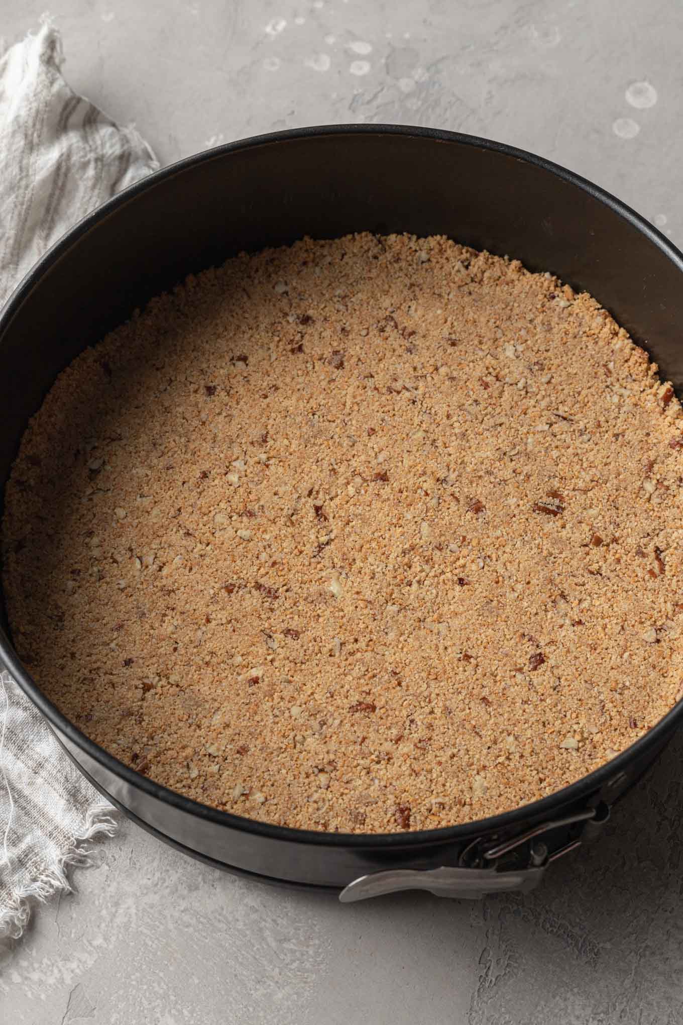 An overhead view of a pecan crust for a cheesecake in a springform pan. 