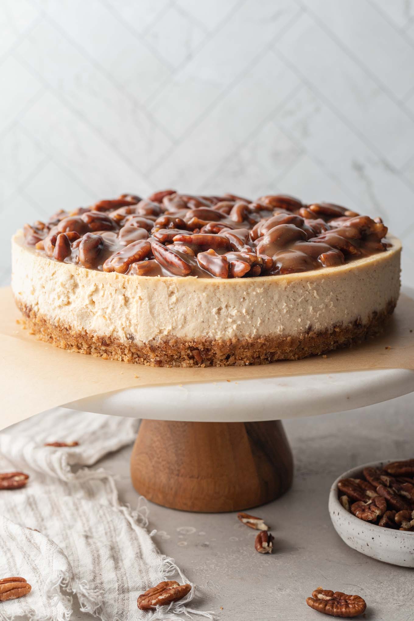 A pecan pie cheesecake on a marble cake stand. 