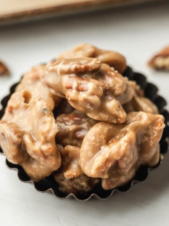 Several pecan pralines in a small tin.